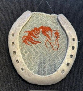 Decorative item with a horseshoe and red design on a textured surface